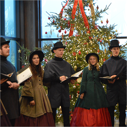 christmas carolers singing in front of christmas tree