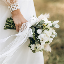 A bride in a white gown holds a bouquet of white flowers