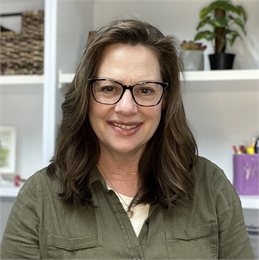 Author Rebecca Wojahn pictured wearing glasses and a green button up shirt.
