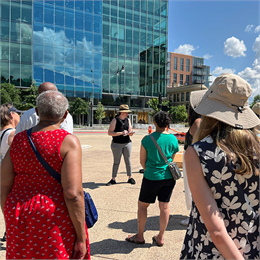 Group stands outside, listening to tour guide