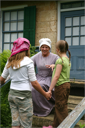 A tour guide in costume talks with two students.