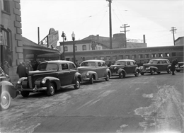 Four Nash automobiles parked outside a train station.